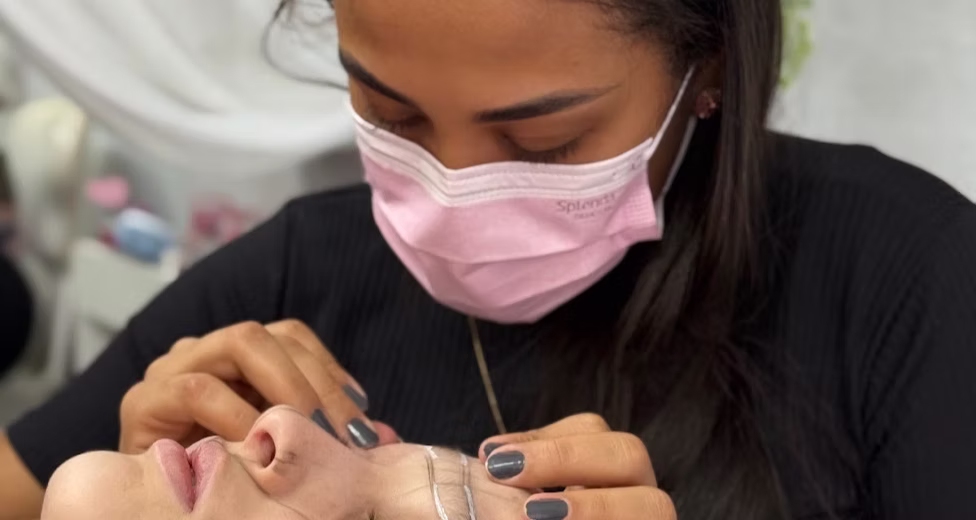 Aluna do Instituto Lilly Santos aplicando extensão de cílios em modelo durante o curso presencial em Itajaí